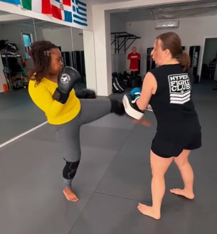 Female kickboxer practicing striking techniques with trainer at Johnny Karate NYC gym.