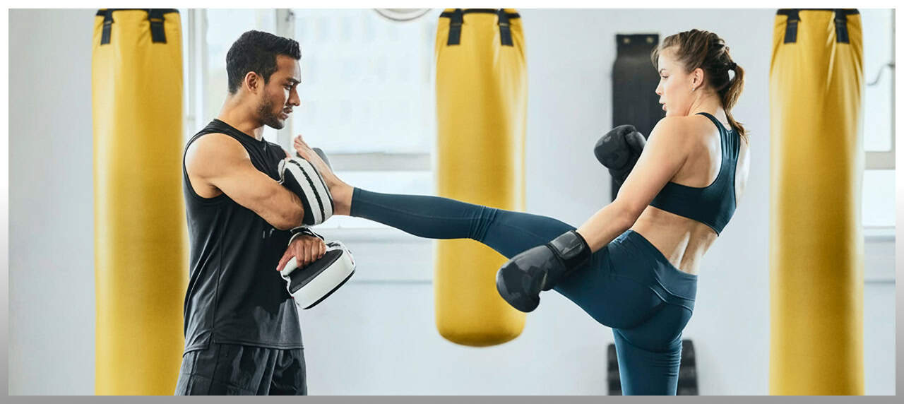 Woman practicing kickboxing with trainer at Johnny Karate NYC gym.