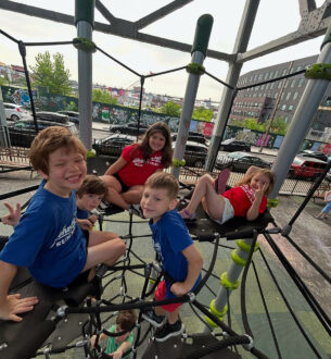 Kids climbing and playing on a modern outdoor playground in NYC.