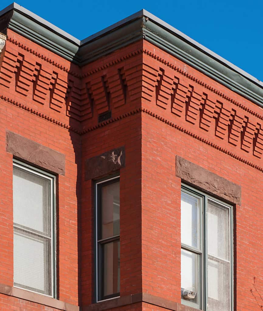 Restoration of historic brick masonry and tuckpointing on a red brick building.