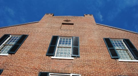 Historic brick masonry with black window shutters and detailed tuckpointing.
