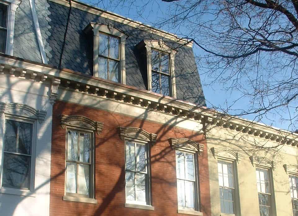 Historic brick building with detailed masonry and window trim under a clear blue sky.
