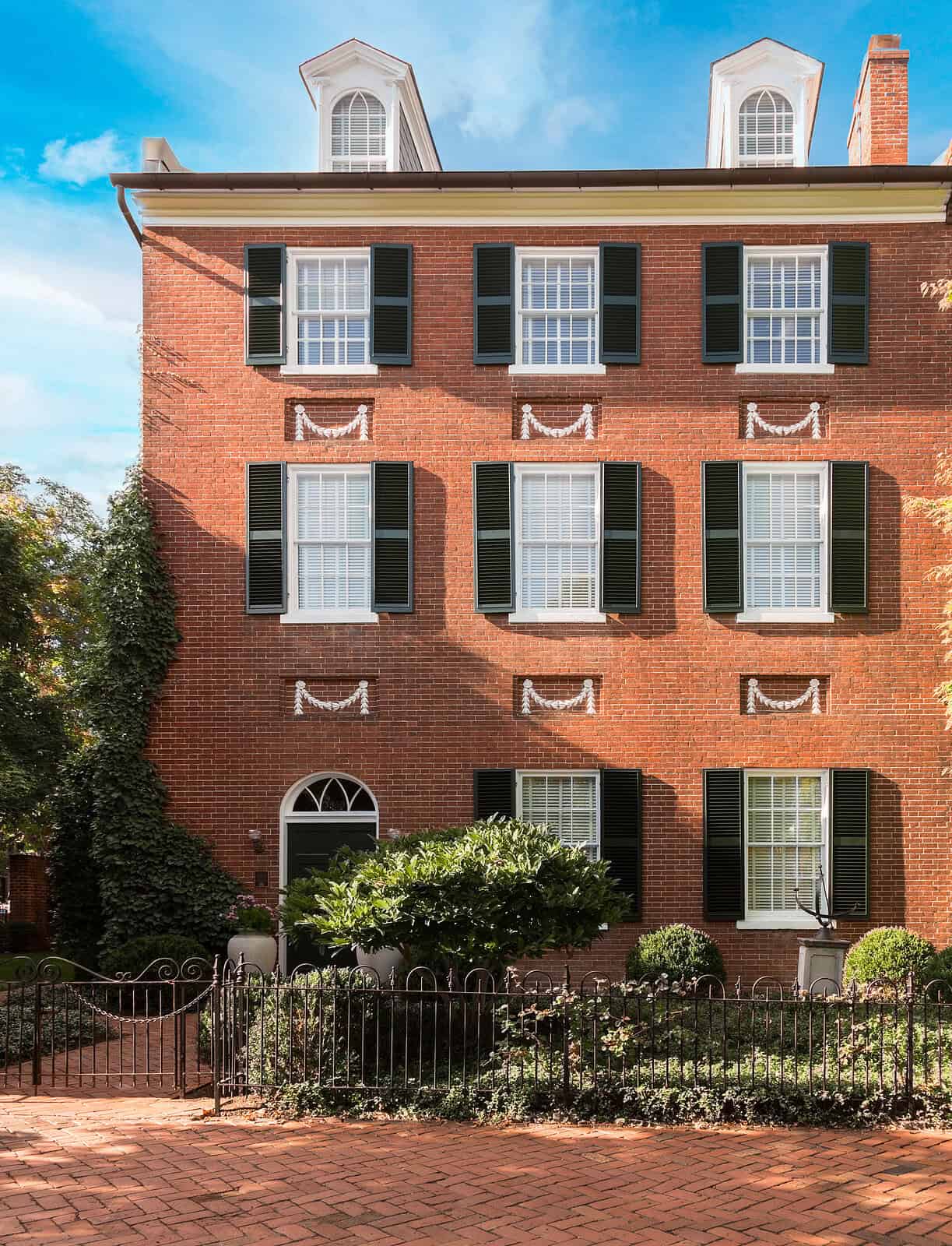 Historic brick building with black shutters and decorative masonry details.