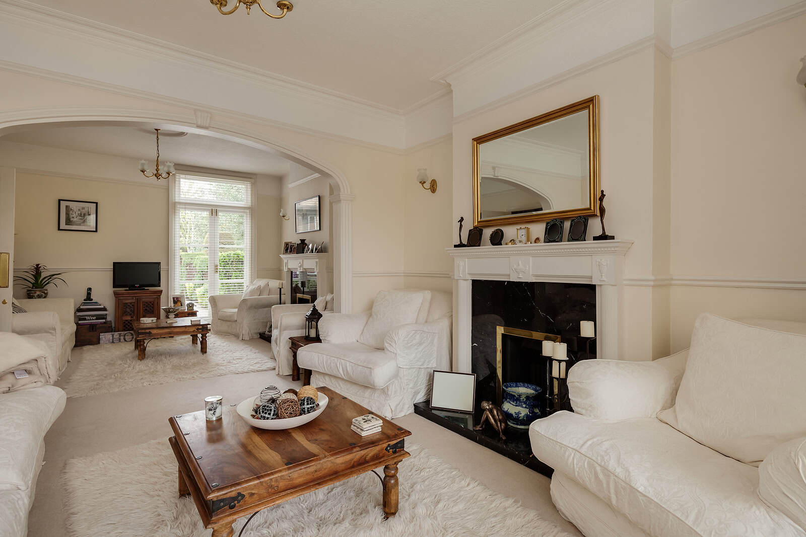 Elegant living room with classic decor, fireplace, and large windows in a historic home.