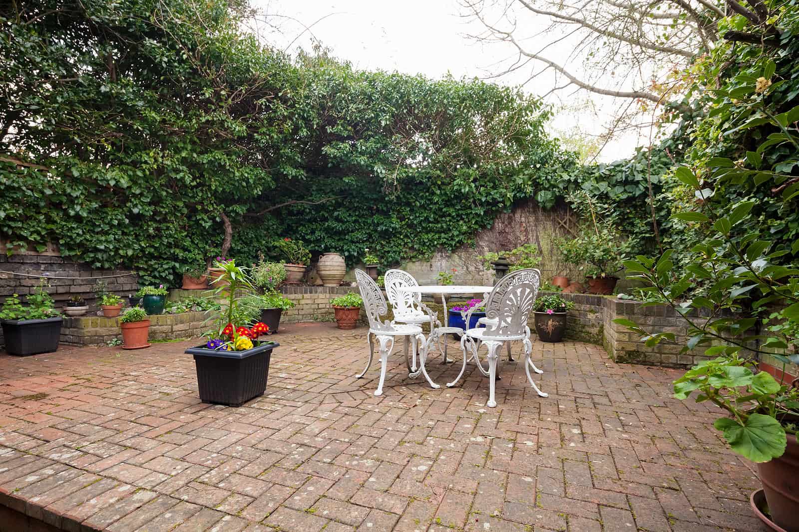 Outdoor brick patio with garden furniture and potted plants, showcasing masonry work.