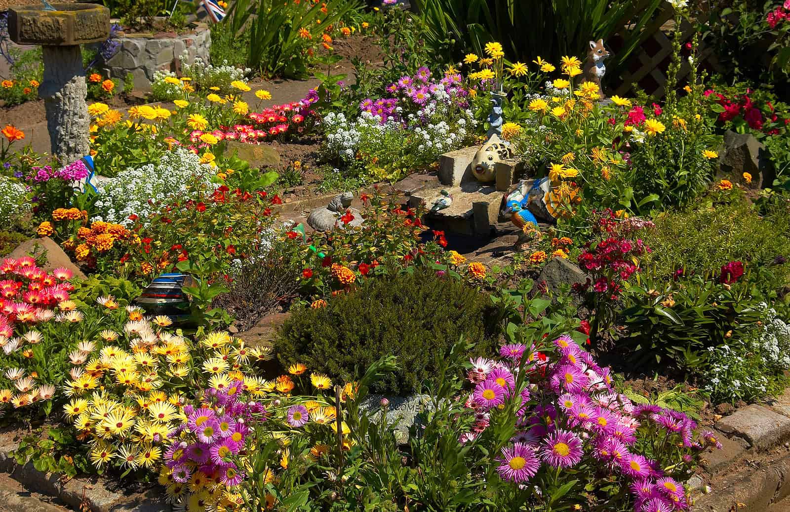 Beautiful garden with colorful flowers and decorative statues, showcasing well-maintained masonry an.