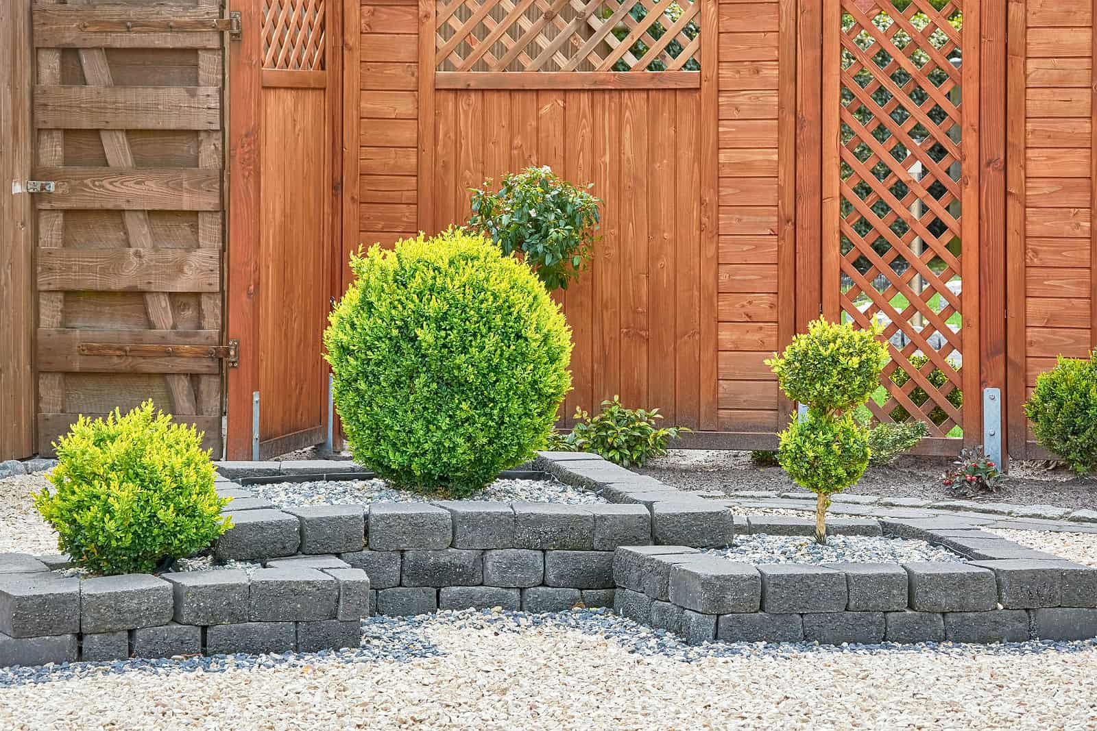 Well-maintained garden with stone retaining wall and lush green bushes.