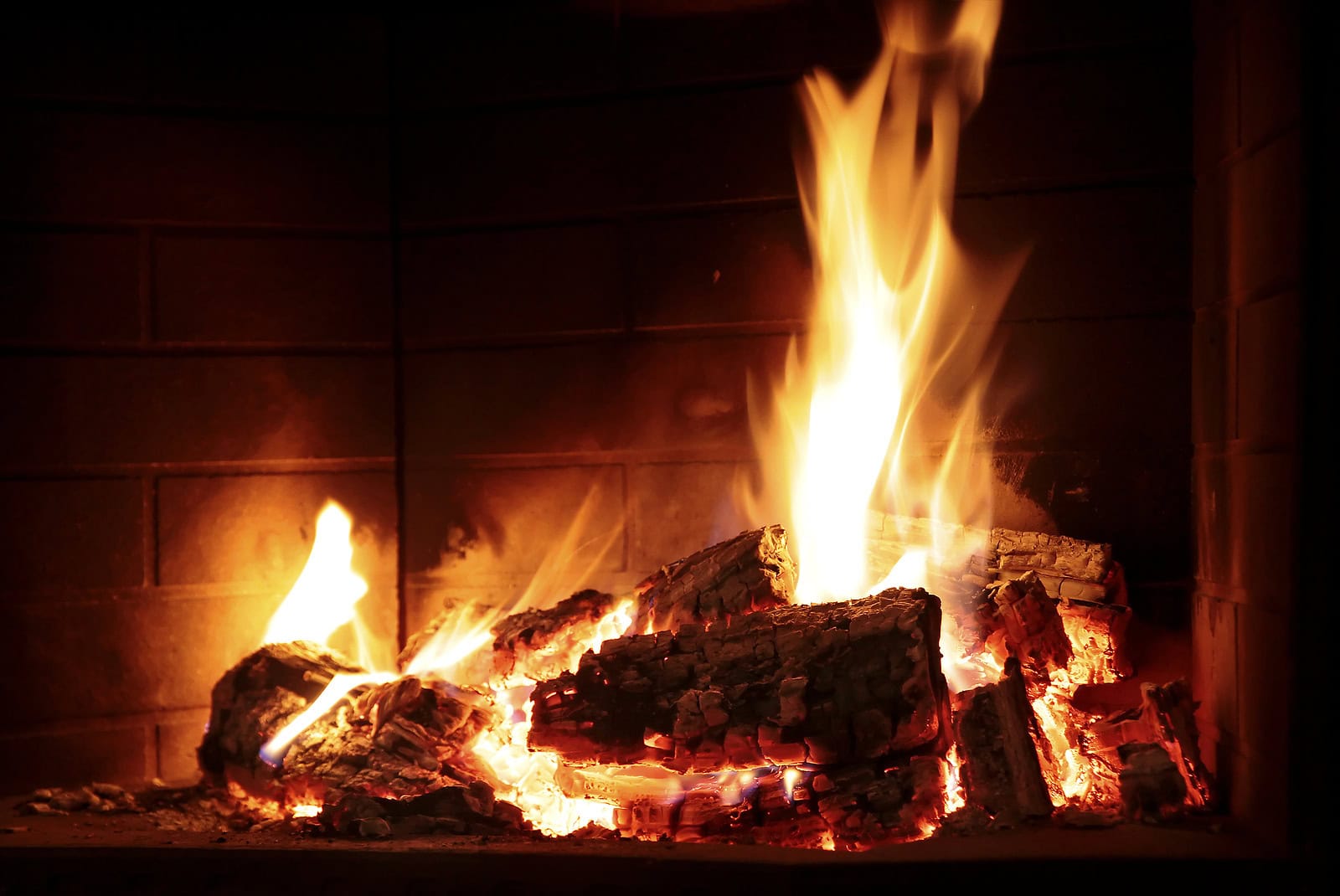 Close-up of a traditional fireplace with glowing embers and flames, showcasing historic masonry work.