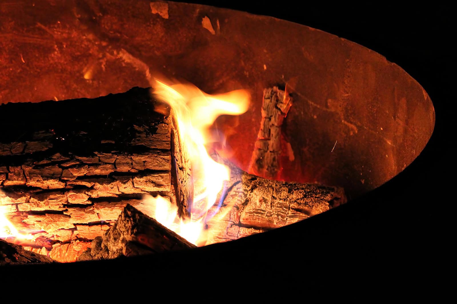 Close-up of a glowing fire in a forge or kiln with burning logs and flames.