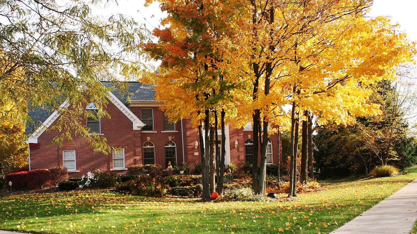 Historic brick house with autumn trees and well-maintained lawn.