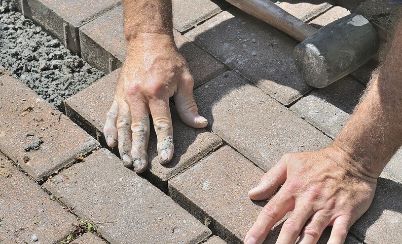 Close-up of hands laying bricks for a masonry project, showing craftsmanship and precision.