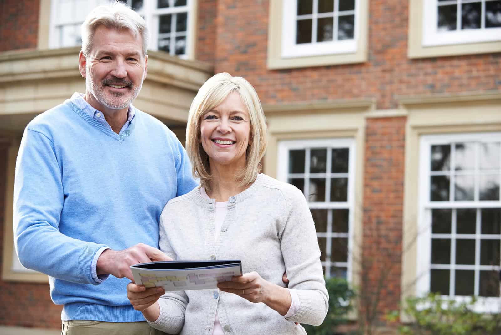 Happy couple reviewing documents in front of a historic brick building.