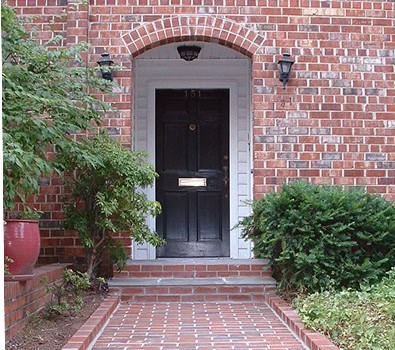 Close-up of a historic brick masonry building with a black door and brick archway.