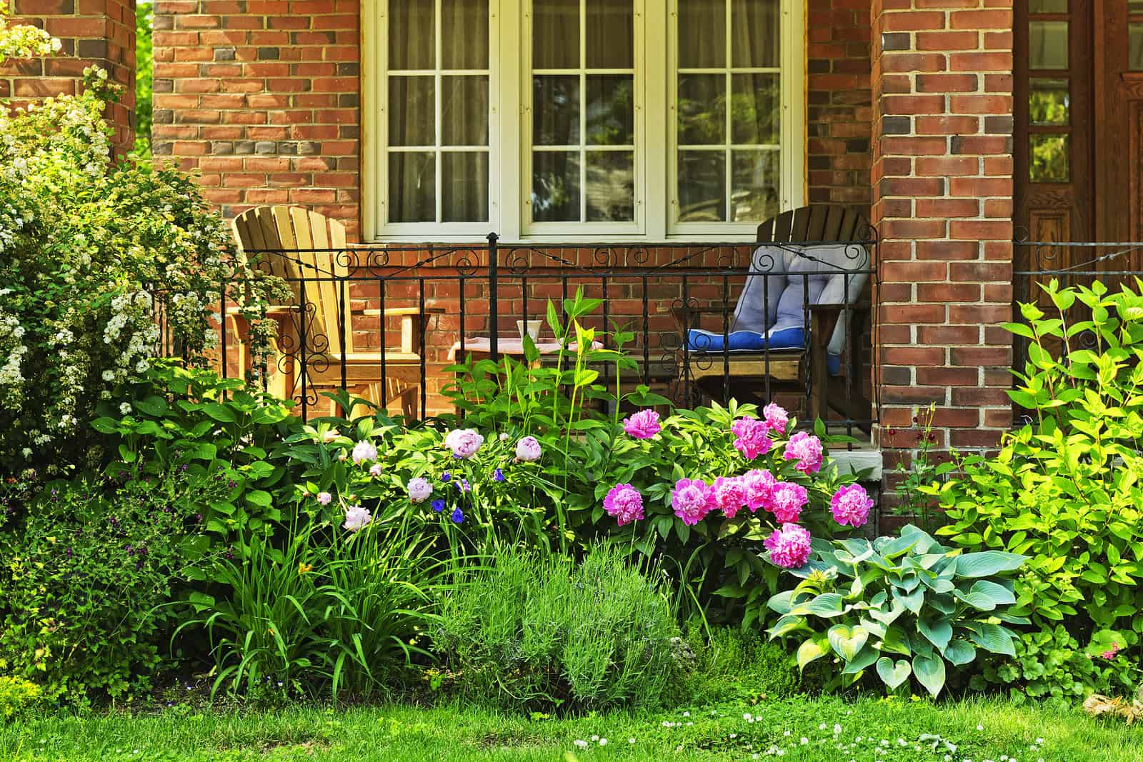 Beautiful brick house with a garden and porch, showcasing historic masonry and lush greenery.