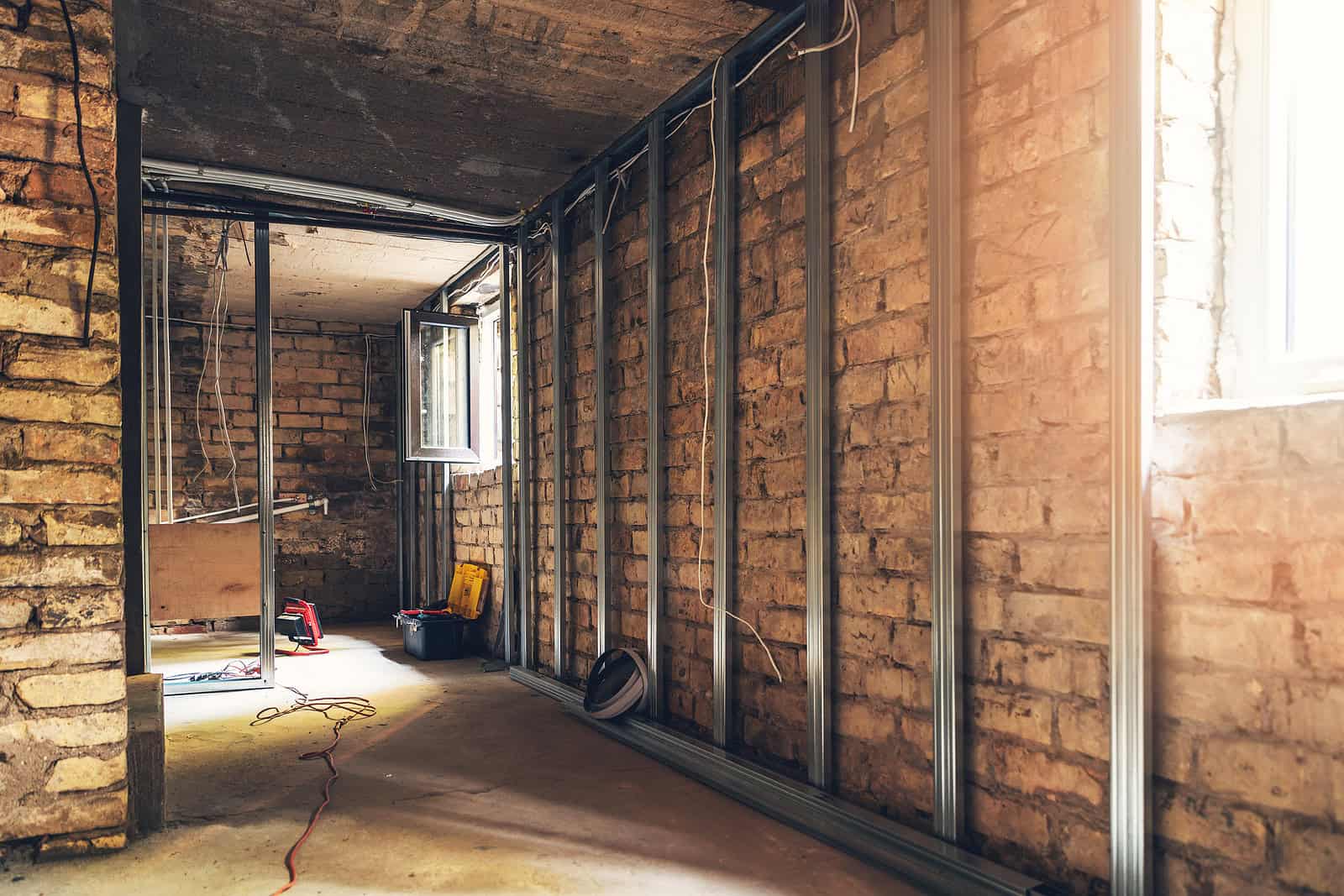 Interior view of brick wall renovation with metal framing in progress.