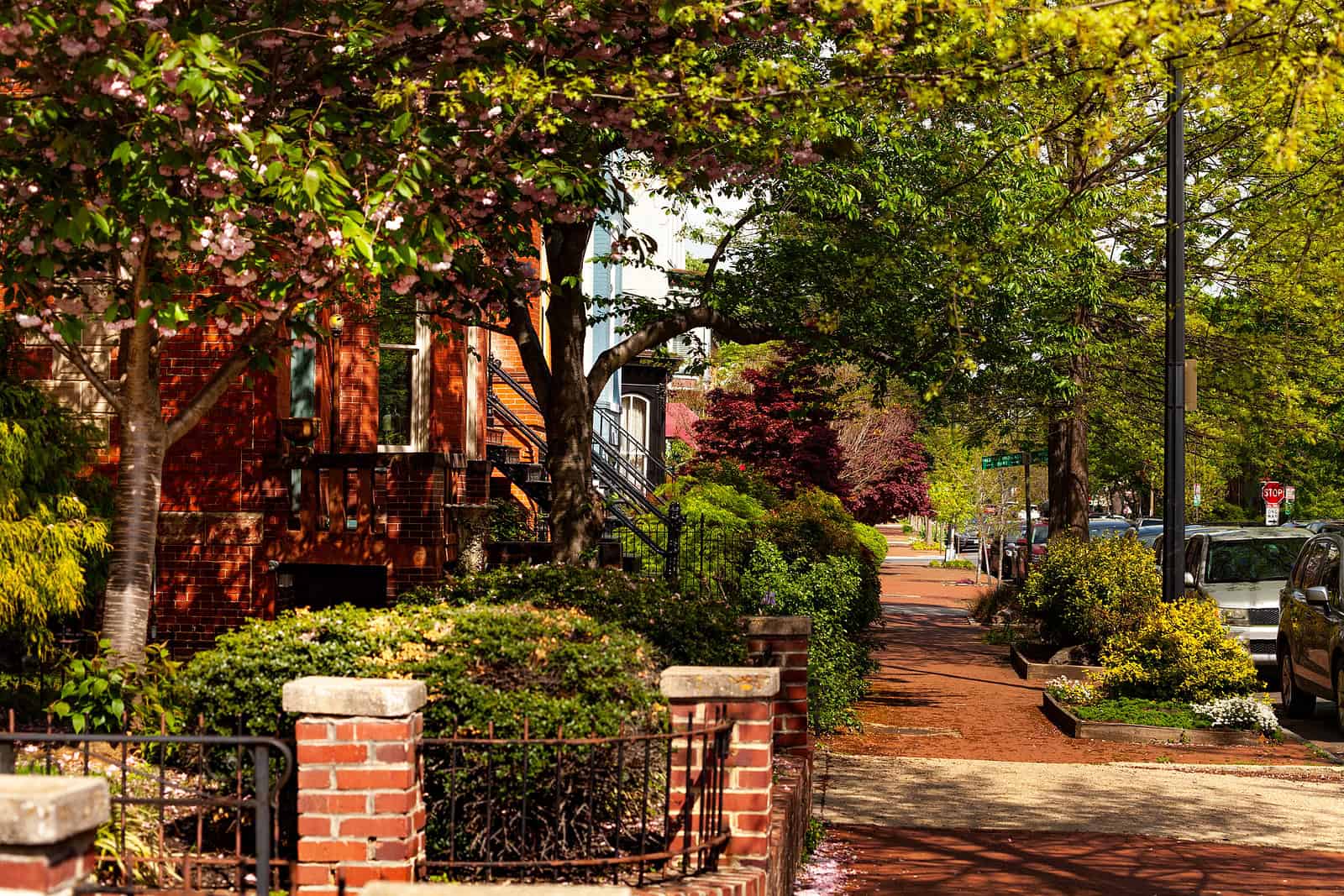 Historic brick building with detailed masonry and lush greenery in a neighborhood setting.