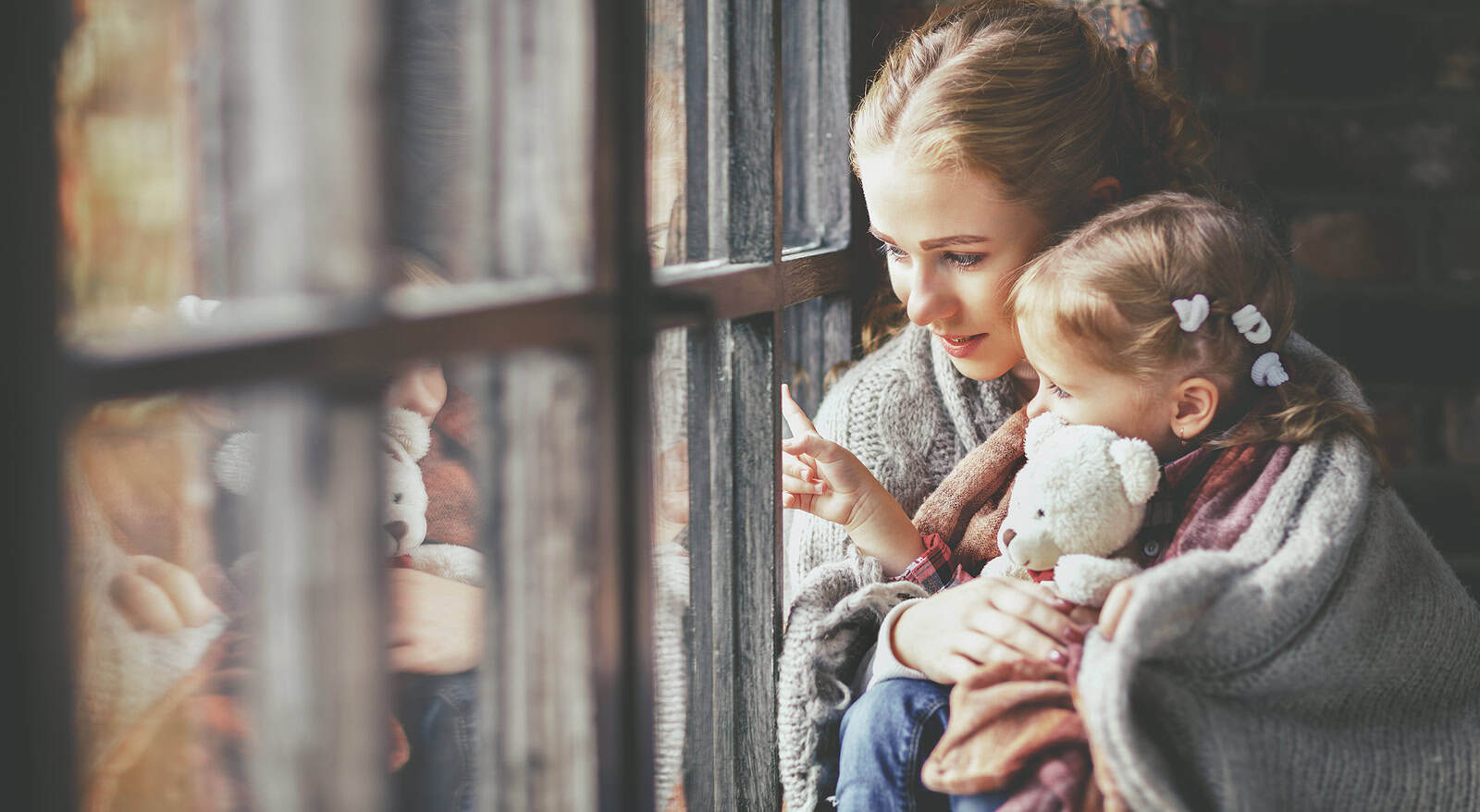 Close-up of a woman and young girl looking through a historic brick window, highlighting masonry res.