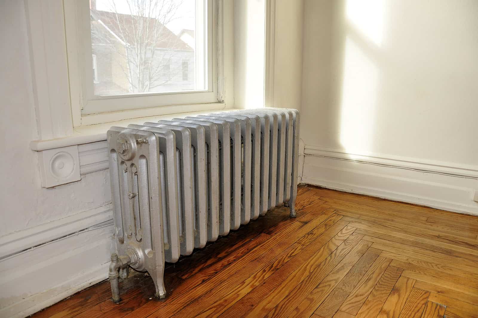 Radiator in a historic room with white walls and wooden flooring, showcasing traditional masonry and.