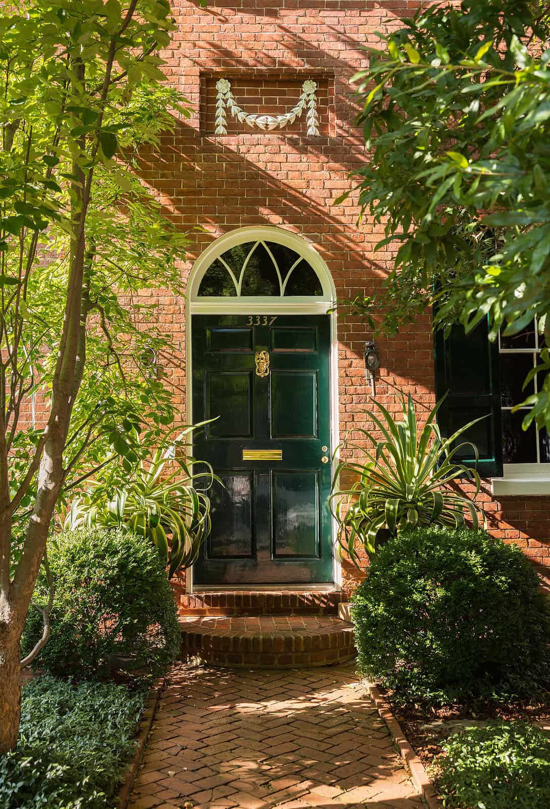 Historic brick masonry entrance with elegant black door and decorative arch window.
