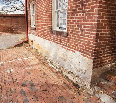 Historic brick building with masonry and tuckpointing work on the foundation.