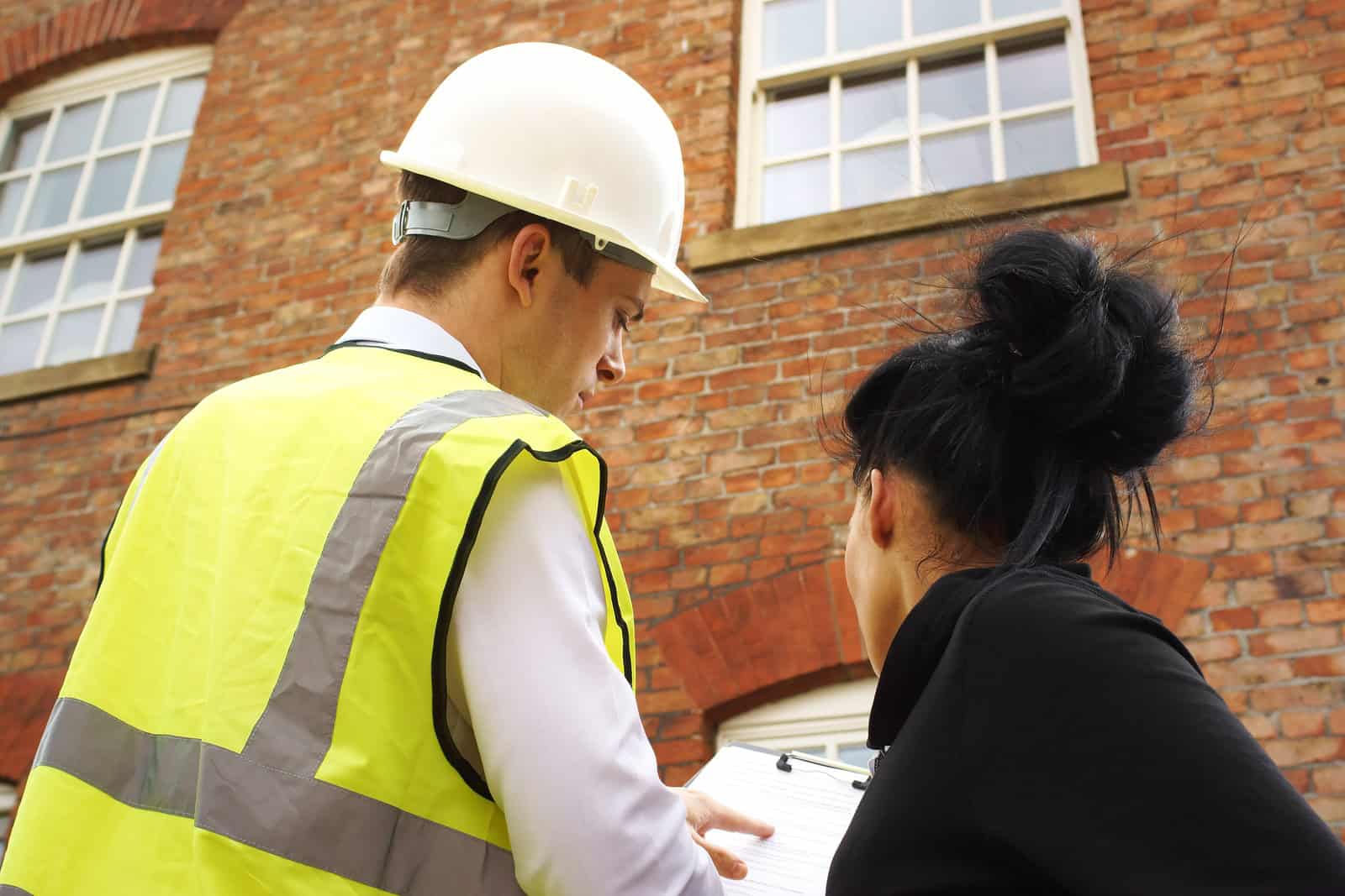 Construction professionals inspecting historic masonry and tuckpointing work on a brick building.