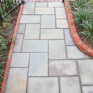 Close-up of a well-maintained stone walkway with brick edging and surrounding greenery.