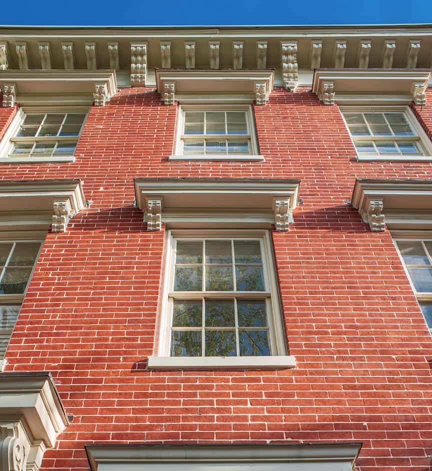 Close-up of a historic red brick building with detailed masonry and window trim.