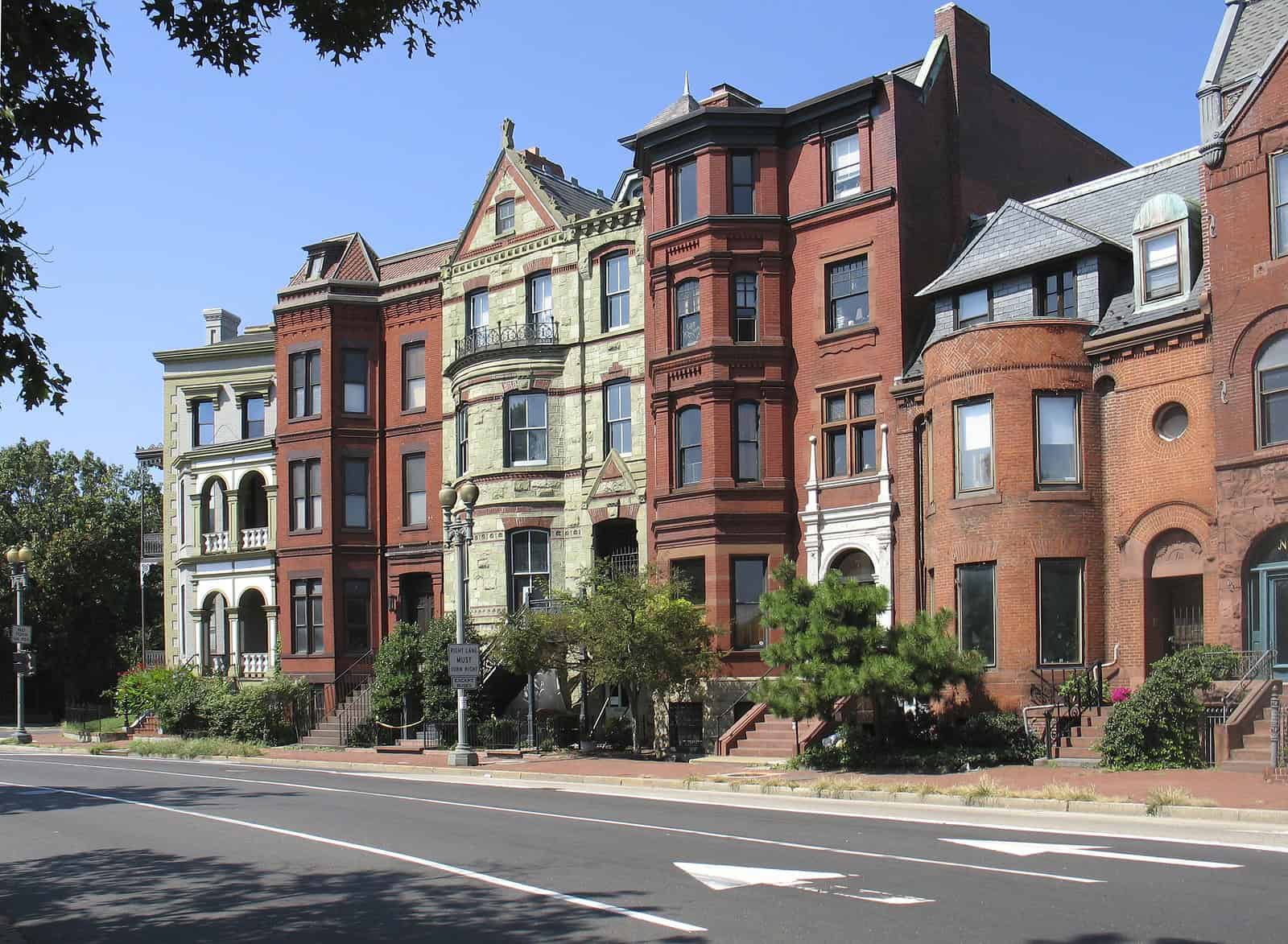 Row of historic brick buildings with detailed masonry and tuckpointing in a city neighborhood.