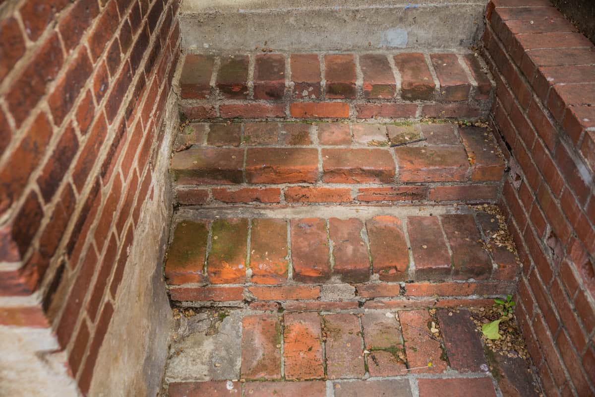 Old brick stairs with weathered mortar and moss growth.
