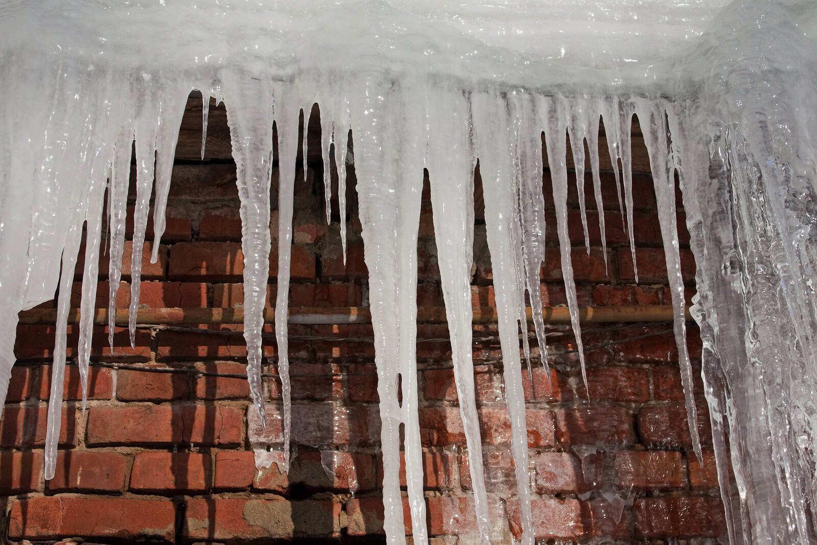 Icicles hanging from a brick wall during winter, showcasing historic masonry details.
