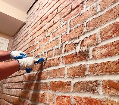 Close-up of historic brick wall being tuckpointed by a worker.