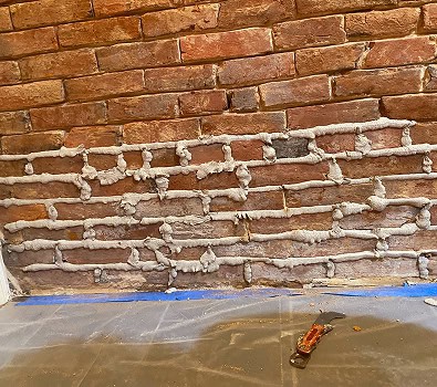 Close-up of historic brick wall with tuckpointing work in progress.