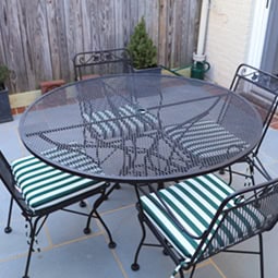 Outdoor patio table with glass top and striped cushions.