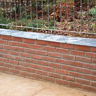 Restoration of historic masonry and tuckpointing on a brick wall.