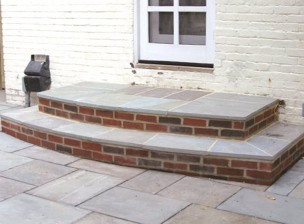 Brick and stone masonry steps leading to a white door with a window.