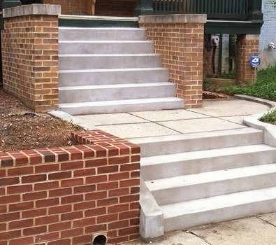 Concrete stairs with brick wall accents and sidewalk in front.
