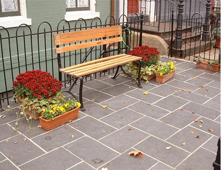Bench with flower planters on a paved sidewalk in front of a historic building.