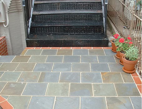 Historic masonry and tuckpointing work on a building entrance with brick and stone paving.
