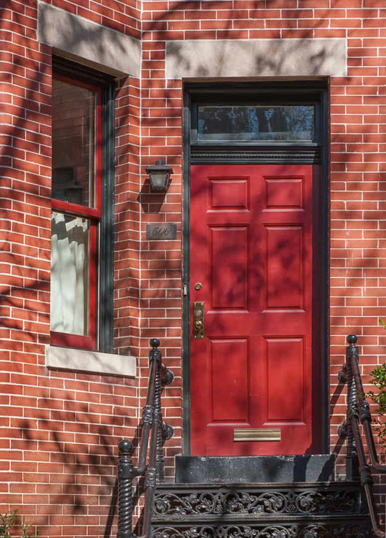 Close-up of a historic brick building with a red door and detailed masonry work.