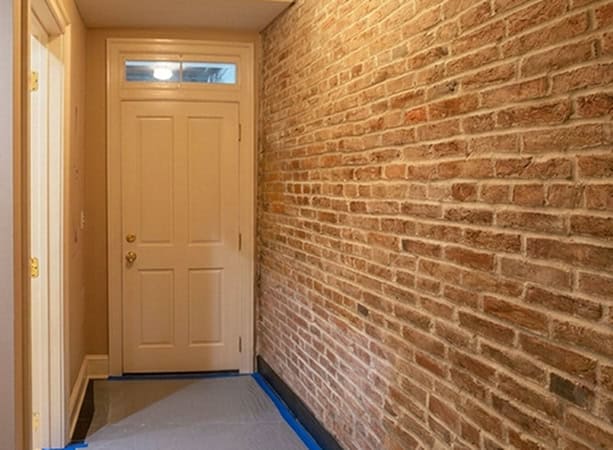 Interior brick wall restoration with tuckpointing and masonry work in a historic building.