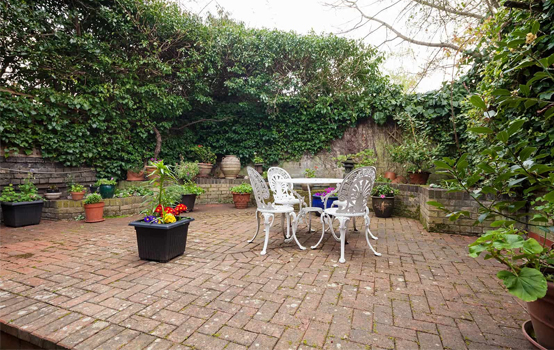 Outdoor brick patio with garden furniture and potted plants, showcasing masonry work.